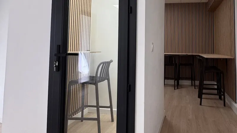 La phone box du bâtiment E2 : porte vitrée noire et tabouret
